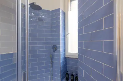 a blue tiled shower in a bathroom with a window at Secret Terrace by Rental in Rome in Rome