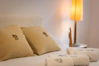 a bed with white sheets and pillows and a lamp at Secret Terrace by Rental in Rome in Rome