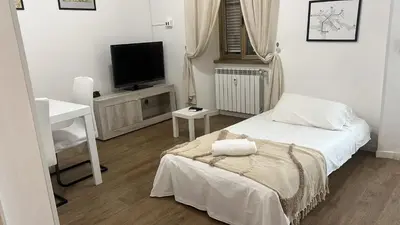 a white bedroom with a bed and a television at Casa Roma in Rome