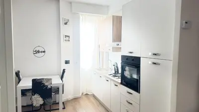 a kitchen with white cabinets and a desk and a tv at Casa Roma in Rome