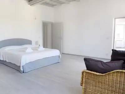 a white bedroom with a bed and a chair at Spacious, Modern, Bright Apartment, near Piazza Navona! in Rome