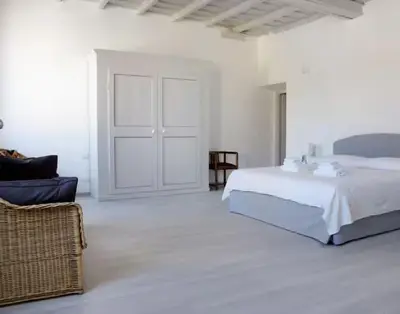 a white bedroom with a bed and a chair at Spacious, Modern, Bright Apartment, near Piazza Navona! in Rome
