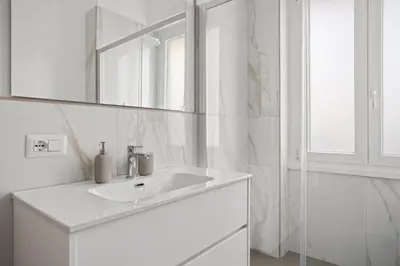 a white bathroom with a sink and a mirror at Urban Loft - San Giovanni by RHR in Rome
