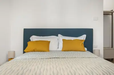 a bed with two yellow pillows and a blue headboard at Urban Loft - San Giovanni by RHR in Rome