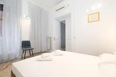 a white room with a bed and a chair at LCGrandTour Donatello in Rome