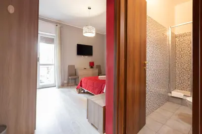 a room with a bedroom with a red bed and a television at Affittacamere Alpino 76 in Rome