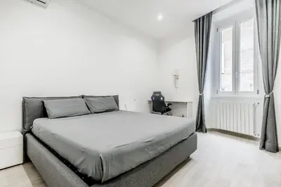 a white bedroom with a bed and a window at The Trastevere Apartment in Rome