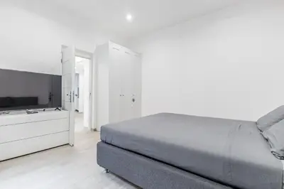 a white bedroom with a bed and a dresser at The Trastevere Apartment in Rome