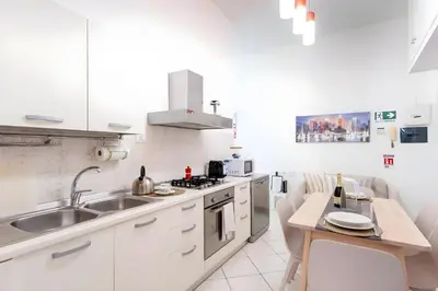 a kitchen with white cabinets and a sink and a table at Elegantis Giolitti Suite Apartment with Private Balcony in Rome