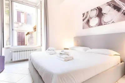a white bedroom with a large white bed and a window at Elegantis Giolitti Suite Apartment with Private Balcony in Rome
