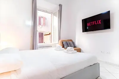 a white bedroom with a bed and a tv on a wall at Elegantis Giolitti Suite Apartment with Private Balcony in Rome