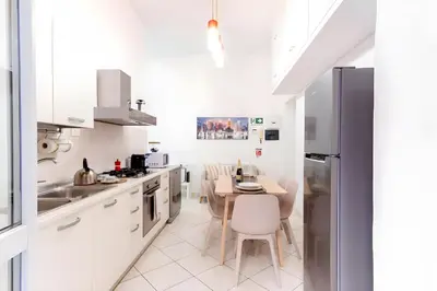 a kitchen with white cabinets and a table with chairs at Elegantis Giolitti Suite Apartment with Private Balcony in Rome