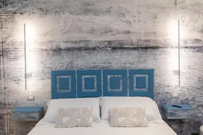 a bed with a blue headboard and two tables at ARIOSTO'S Luxury Rooms in Rome