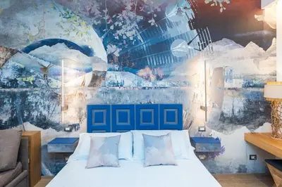 a bedroom with a bed with a painting on the wall at ARIOSTO'S Luxury Rooms in Rome