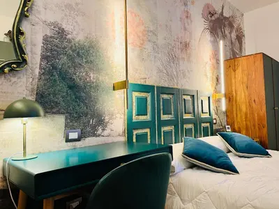 a bedroom with a desk and a bed with blue pillows at ARIOSTO'S Luxury Rooms in Rome