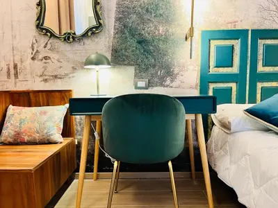 a bedroom with a desk and a green chair at ARIOSTO'S Luxury Rooms in Rome