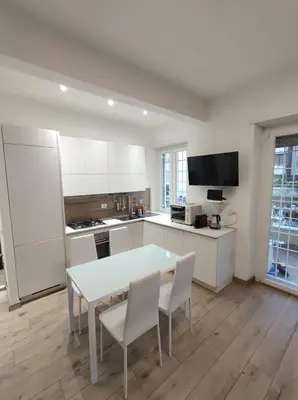 a kitchen with white cabinets and a table and chairs at Annalisa Home in Rome