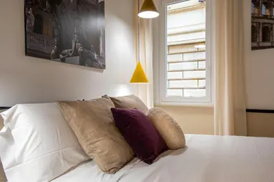 a bedroom with a white bed with pillows and a window at Pantheon Suites Rome 1 in Rome