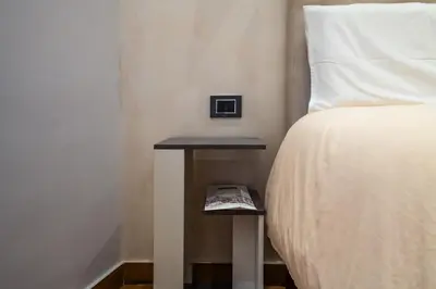 a side table next to a bed with a book on it at AP Royal suite guesthouse in Rome