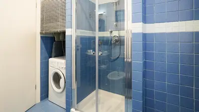 a blue tiled bathroom with a washing machine at La Casa che Vorrei in Rome