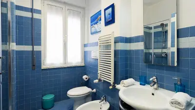 a blue tiled bathroom with a toilet and a sink at La Casa che Vorrei in Rome