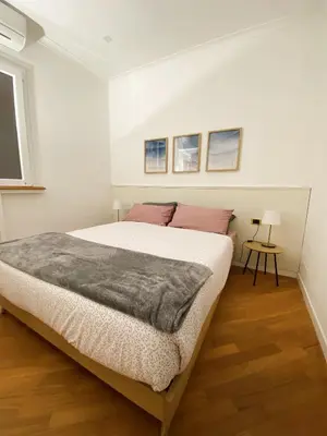 a white bedroom with a large bed and a window at LovingRome Colosseum in Rome