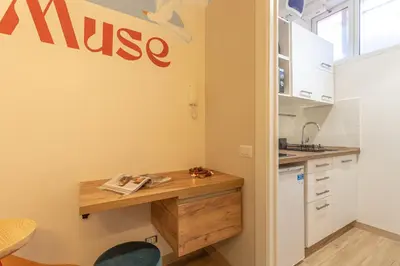 a kitchen with a wooden desk and a nisse sign on the wall at Le Muse Suites in Rome