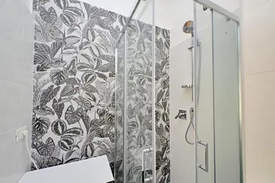 a bathroom with a shower with a black and white wallpaper at Trastevere 3 apartments by Flatinrome in Rome