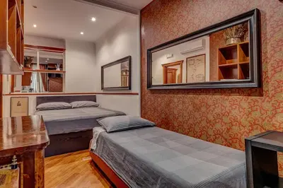 a bedroom with two beds and a mirror on the wall at Vatican Luxury Suite Bragadin in Rome