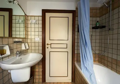 a bathroom with a sink and a tub and a door at Crimson Guest House in Rome