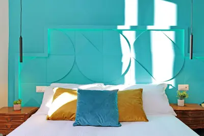 a bed with a blue headboard and white pillows at Domus Augustea - San Giovanni Sunset Suites in Rome