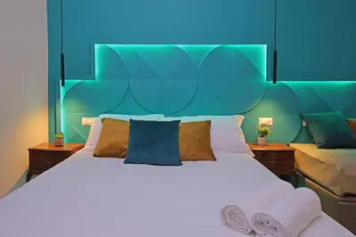 a bedroom with a large white bed with a blue headboard at Domus Augustea - San Giovanni Sunset Suites in Rome