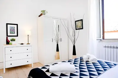 a white bedroom with a bed and a dresser at Bella Nonna in Rome