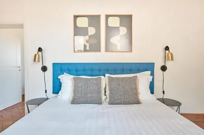 a bed with a blue headboard and two lamps at Montevecchio Boutique Apartments in Rome