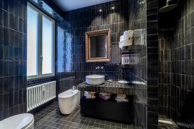 a black tiled bathroom with a sink and a toilet at Bellina Suite Hi Tech Apartment in Rome