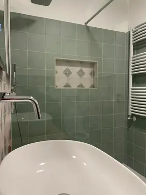 a bath tub in a green tiled bathroom at Bed & Breakfast RCH Roman Central House in Rome