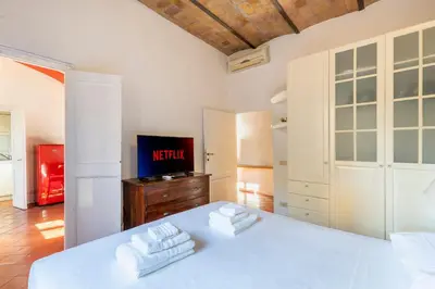 a bedroom with a white bed and a tv at Maison Colosseo in Rome