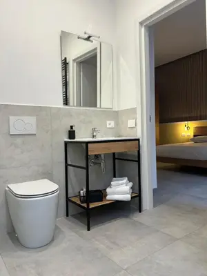 a bathroom with a sink and a toilet and a bed at Lilium Suites in Rome