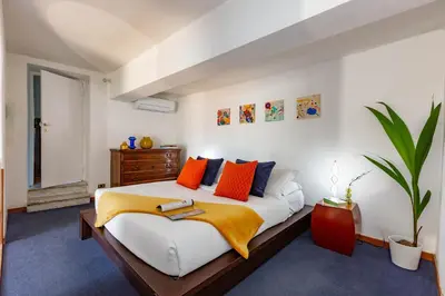 a bedroom with a large bed with orange and blue pillows at Spanish Steps Luxury Apartment in Rome