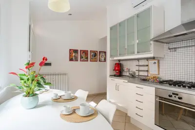 a kitchen with white cabinets and a table and chairs at Terrazza San Lorenzo - Luxury Apartment - Roma Centro in Rome