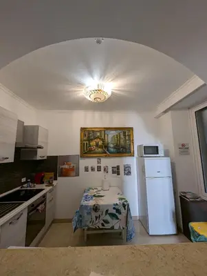 a kitchen with a table and a white refrigerator at Roomz Romestay in Rome
