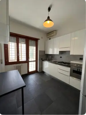 a kitchen with white cabinets and a table in it at Maison del Forte Boccea 108 in Rome