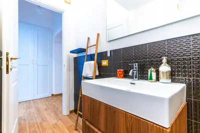 a kitchen with a white sink and black tiles at Casa Fen Palazzo Storico - Re di Roma metro A - 2camere2bagni in Rome