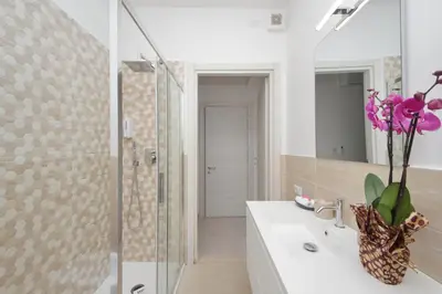 a bathroom with a shower and a sink with a vase of flowers at 4BNB - The Dome TwentyFive in Rome