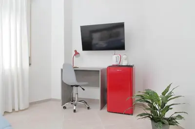 a room with a desk with a red refrigerator and a chair at 4BNB - The Dome TwentyFive in Rome