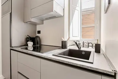 a white kitchen with a sink and a window at Home Sweet Rome Lucina in Rome