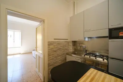 a kitchen with white cabinets and a stove top oven at St Lawrence by BuddyRent in Rome