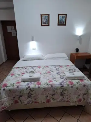 a bed with a floral bedspread and two towels at APARTAMENTo FANTI22 in Rome