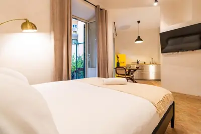 a bedroom with a large white bed and a kitchen at Cunabu Morosini in Rome