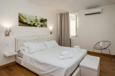 a white bedroom with a white bed with two towels on it at Fabuloucity Fontana di Trevi in Rome